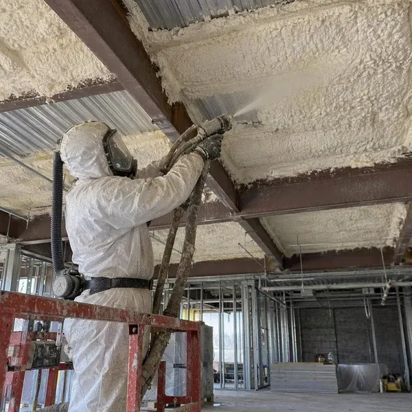 Installer spraying foam under a commercial building roof deck