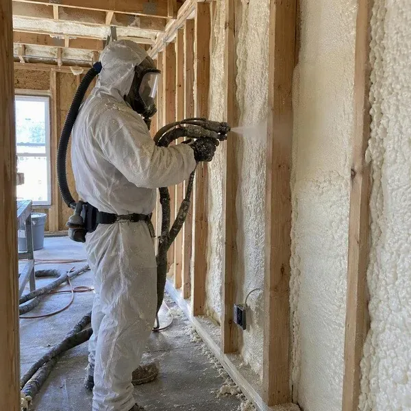 Worker spraying foam inside a newly framed home
