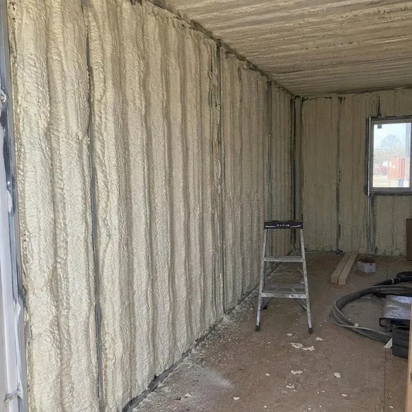 Spray foam covering corrugated shipping container walls
