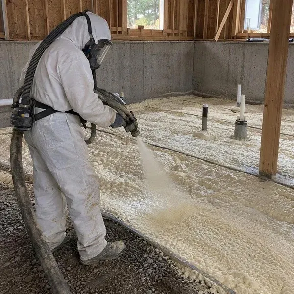 Worker spraying underslab foam across a prepared base